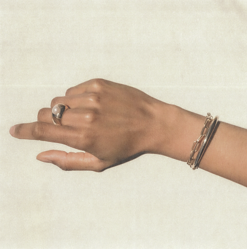 Hand with a ring and bracelet on a beige background